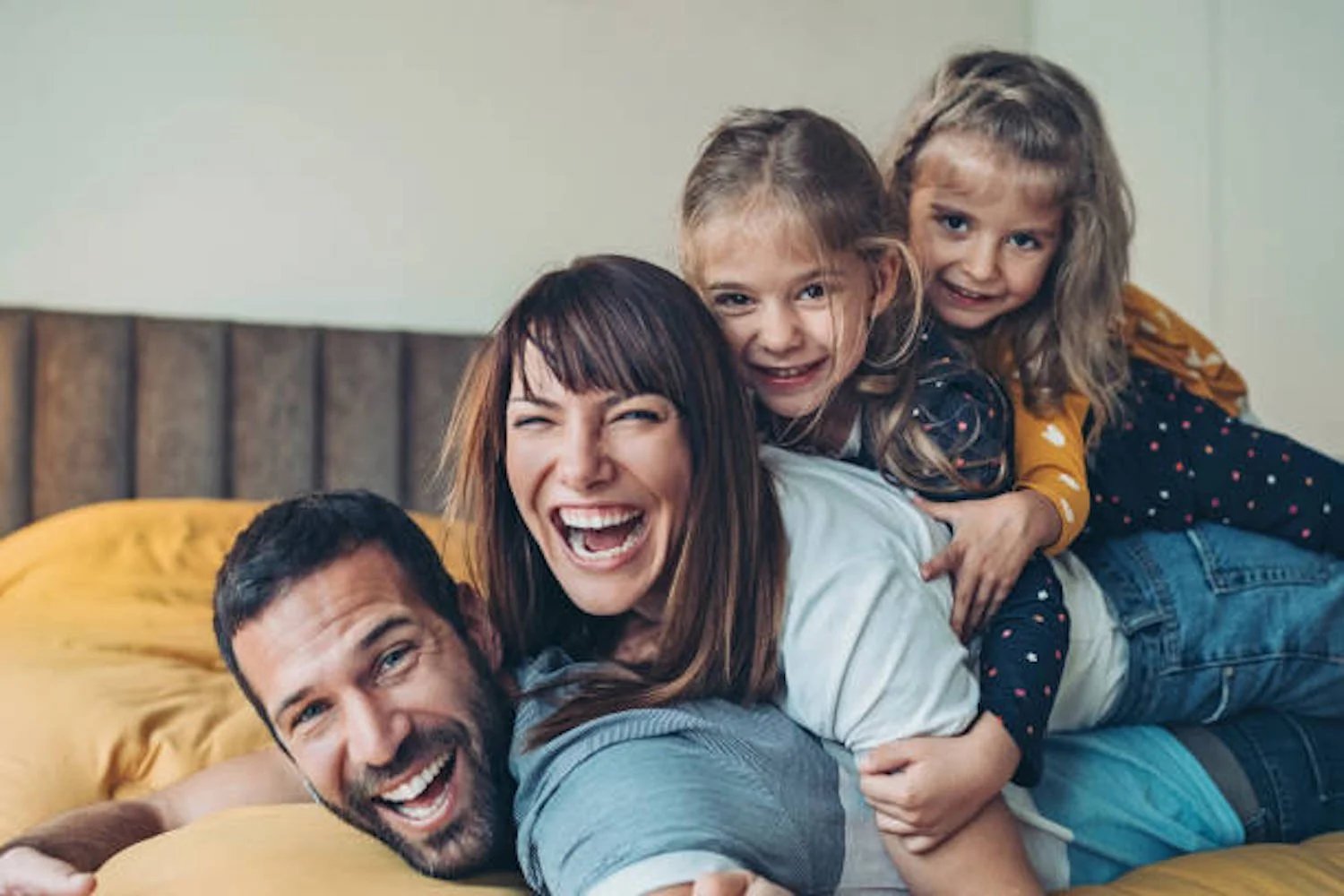 Happy family laughing and playing on a bed.